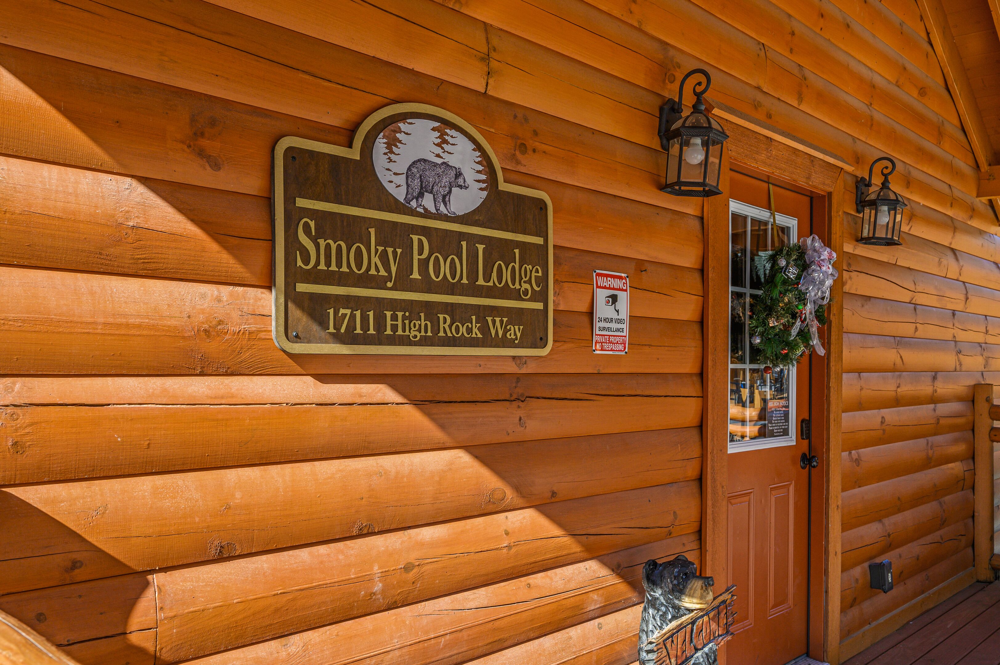 Smoky Pool Lodgen ulkoseinän puinen julkisivu, jossa on kyltti, jossa näkyy paikan nimi ja osoite.