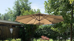 A patio with wicker furniture and a large umbrella. - The York House (Fort Erie)