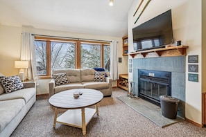 A cozy living room with a sofa, a round coffee table, and a fireplace.