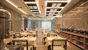 Restaurante com pisos de mármore, mesas com toalhas brancas e design moderno no teto.