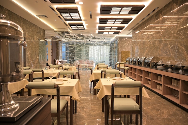 A restaurant with marble floors, tables with white tablecloths, and a modern ceiling design.