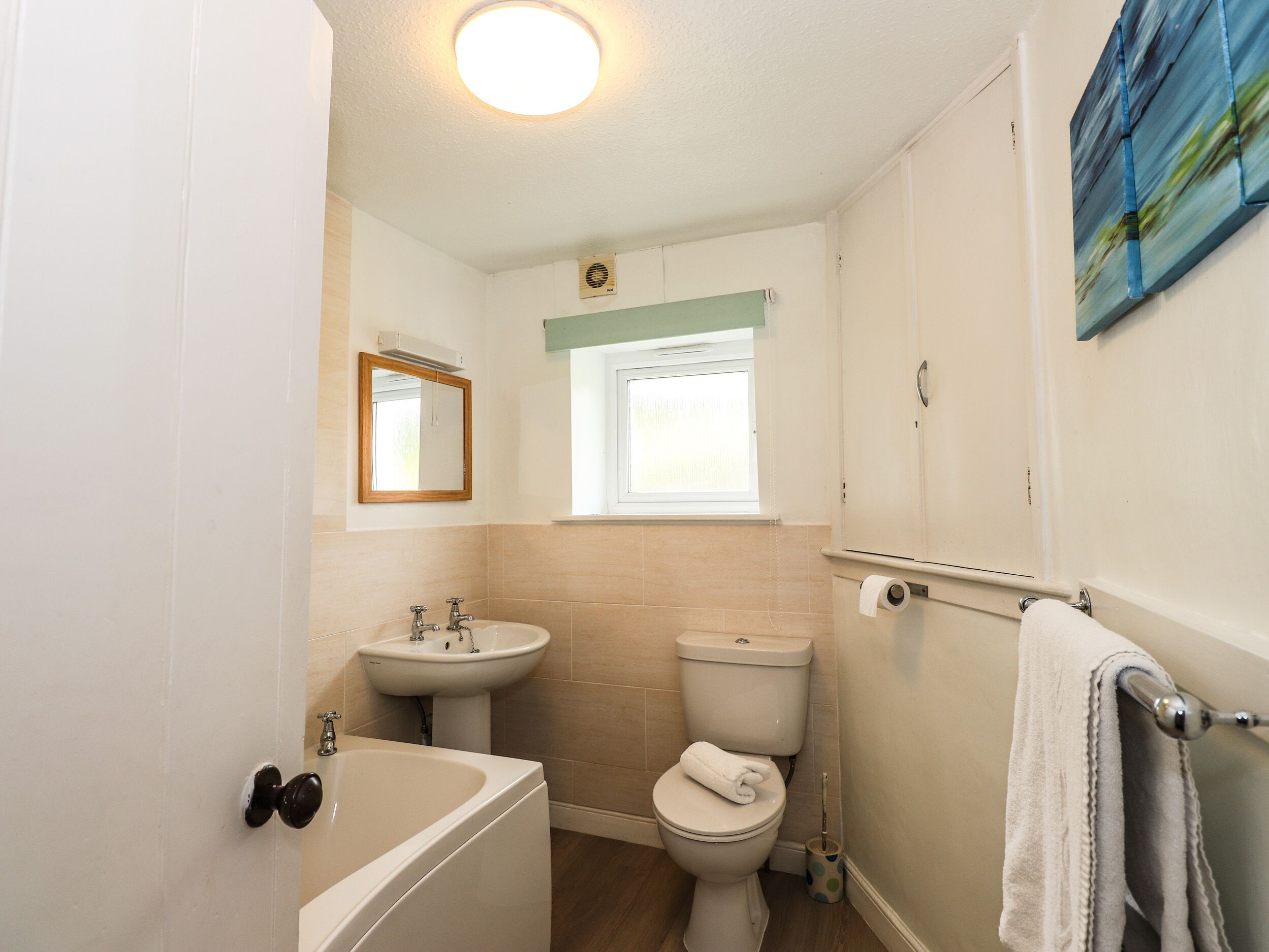 A bathroom with a bathtub, sink, toilet, and a window.