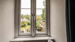 A double-hung window with a view of a garden and a house. - Hilber Cottage (Ambleside)