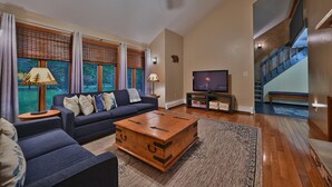 A living room with a sofa, coffee table, and TV. - Spacious Mountain Home with Fireplace, Game Room in Bear Creek Lake Community! (Jim Thorpe)