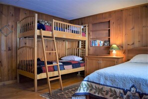 Un letto a castello con una scala, un comodino con una lampada e una libreria.