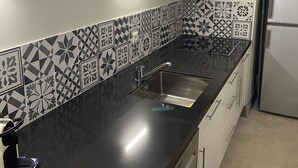 A kitchen with a black countertop, stainless steel sink, and patterned backsplash. - Gite Campanula with communal swimming pool (Saint-Rémy-de-Provence)
