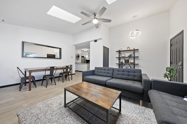 A modern living room with a sofa, coffee table, and dining area.