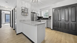 Una cocina moderna con una isla de mármol, electrodomésticos de acero inoxidable y un amplio ventanal que proporciona luz natural.