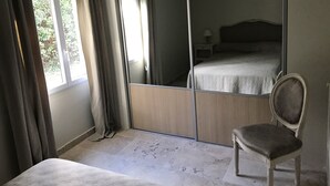 A bedroom with a bed, a chair, a wardrobe, and a window. - Gite Gardenia with a communal swimming pool (Saint-Rémy-de-Provence)