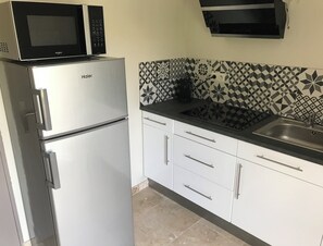 A kitchen with a Haier refrigerator, a microwave, a sink, and patterned backsplash tiles.