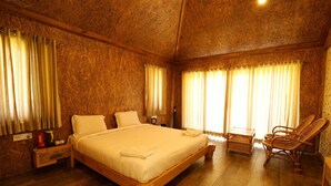 Een slaapkamer met houten lambrisering, een groot bed, twee nachtkastjes, een stoel en een raam met gordijnen.