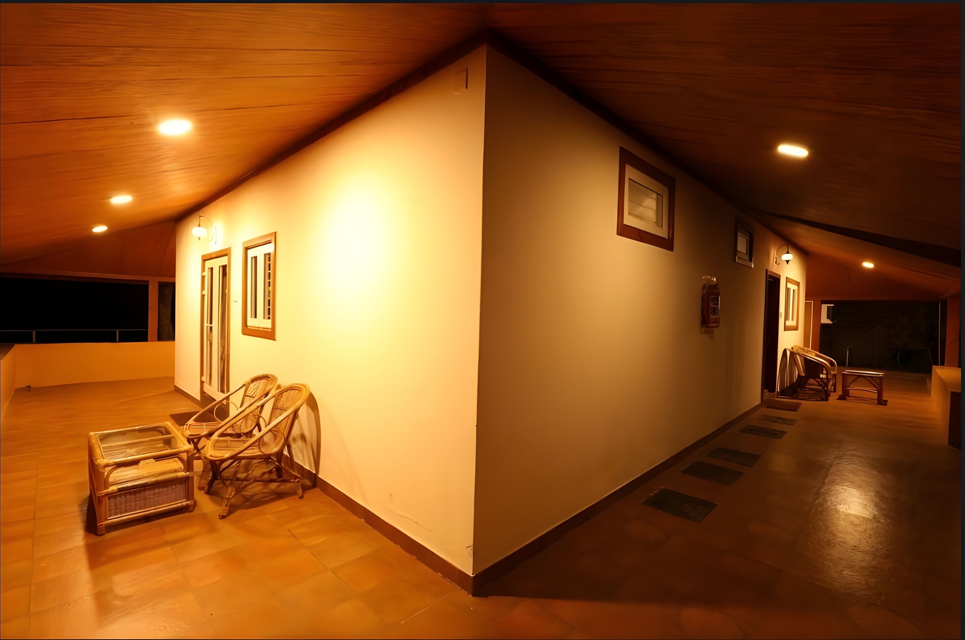 A spacious, well-lit interior with wooden flooring, a high ceiling, and a long corridor with doors and framed pictures.