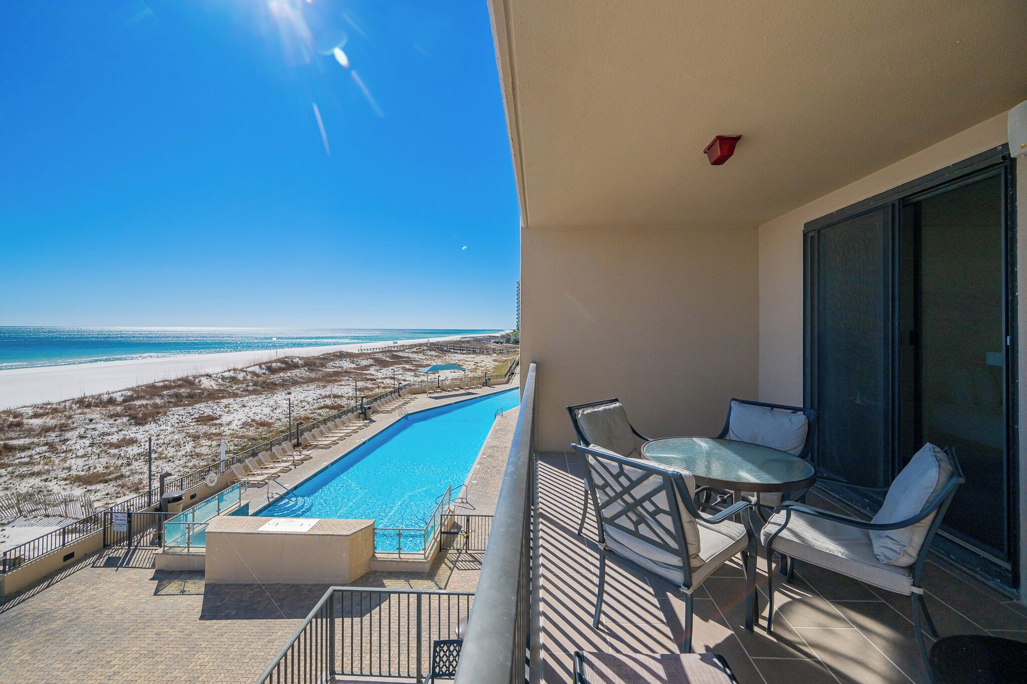 A balcony with a view of a swimming pool and beach.