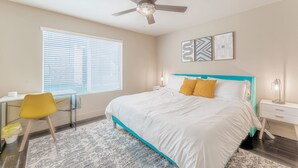 A bedroom with a bed, a desk, a chair, a ceiling fan, and artwork on the wall. - Spacious 1BR close to Downtown w fast wifi w/ pool (Austin)