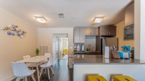 A modern kitchen with dark wood cabinets, stainless steel appliances, and a central island with stools. - Spacious 1BR close to Downtown w fast wifi w/ pool (Austin)