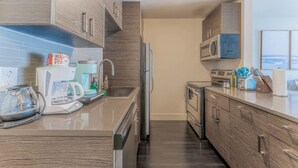 A modern kitchen with wooden cabinets, a stainless steel refrigerator, a microwave, and a coffee maker. - Spacious 1BR close to Downtown w fast wifi w/ pool (Austin)