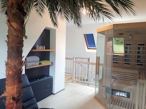 A modern room with a glass partition, a staircase, and a view of the outdoors. - Lerchensteige vacation apartment on 80m² - sauna, bar, 3D TV, Wii, PS4 + VR (Haundorf)