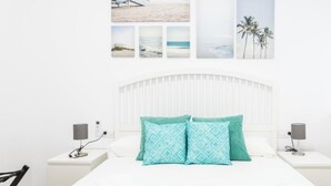 A hotel room with a white bed, two nightstands, a white headboard, and a wall with three framed pictures. - El Arco del Fotografo by Cadiz Time (Cádiz)