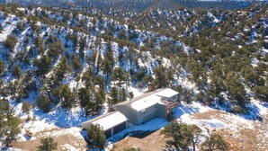 A building with a flat roof, surrounded by snow-covered hills and pine trees. - Book NOW for Summer and Fall Events! In Mountains, 5 mins from Downtown Salida! (Salida)