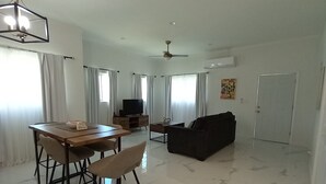 Un grand espace de vie comprenant une table à manger, des chaises, un canapé et un téléviseur.