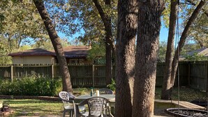 A backyard with a wooden deck, a barbecue grill, and a swing set.