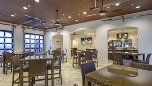 Un restaurant avec de hauts plafonds, des luminaires suspendus et différents types de sièges, notamment des tables et des chaises.