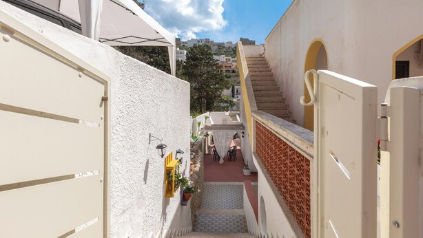 Un estrecho callejón con una escalera que conduce a un edificio con puertas arqueadas y piso de baldosas.