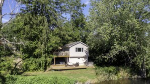 Ein Haus mit Terrasse und Teich davor.