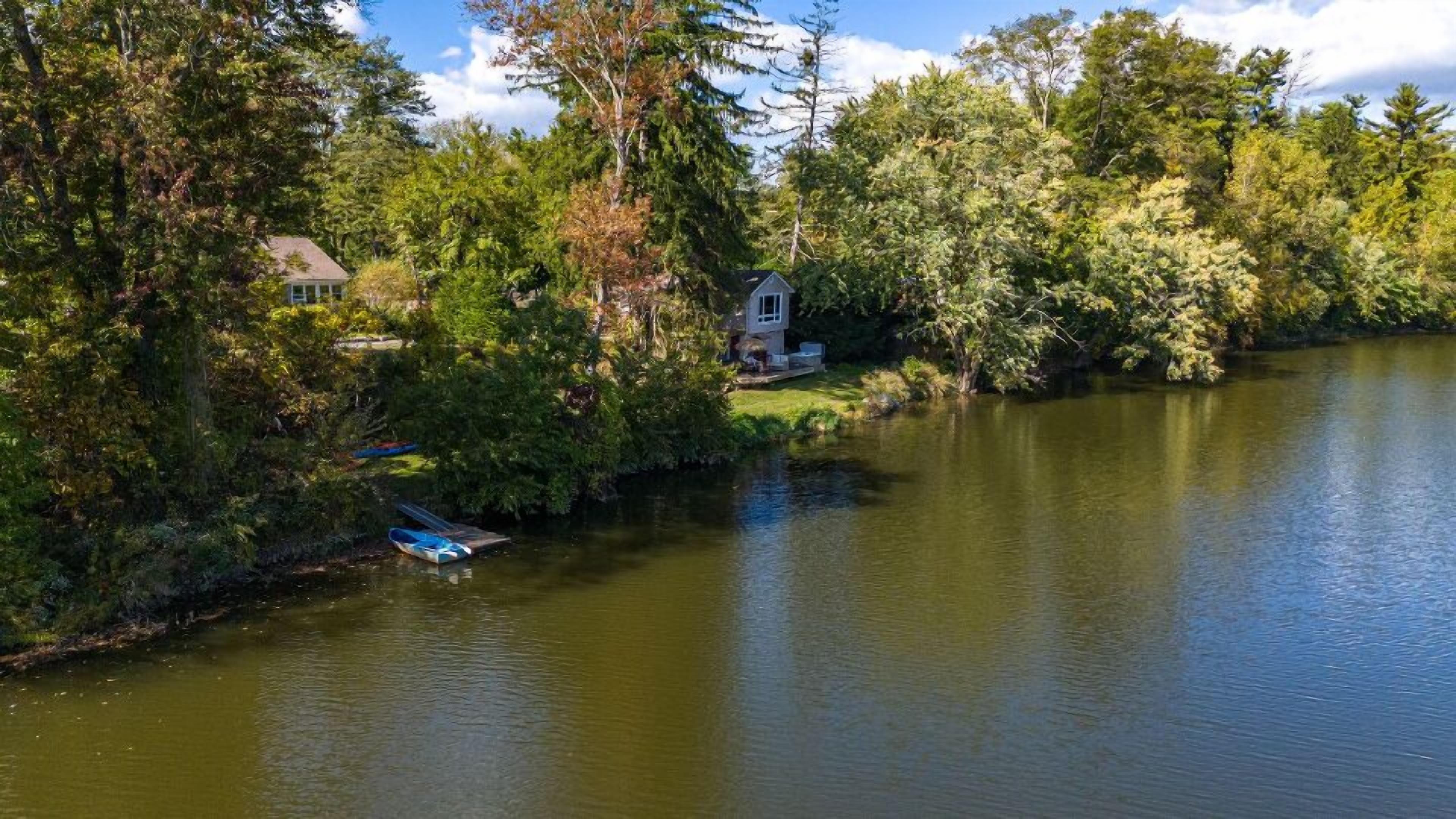 A serene lakeside setting with a small gazebo and a house by the water.