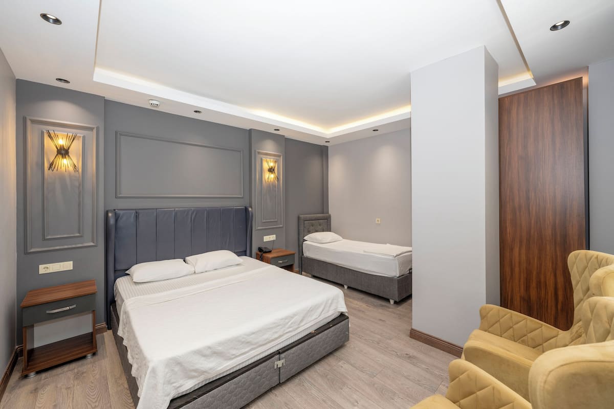 A modern bedroom with two beds, a wooden wardrobe, and built-in lighting.
