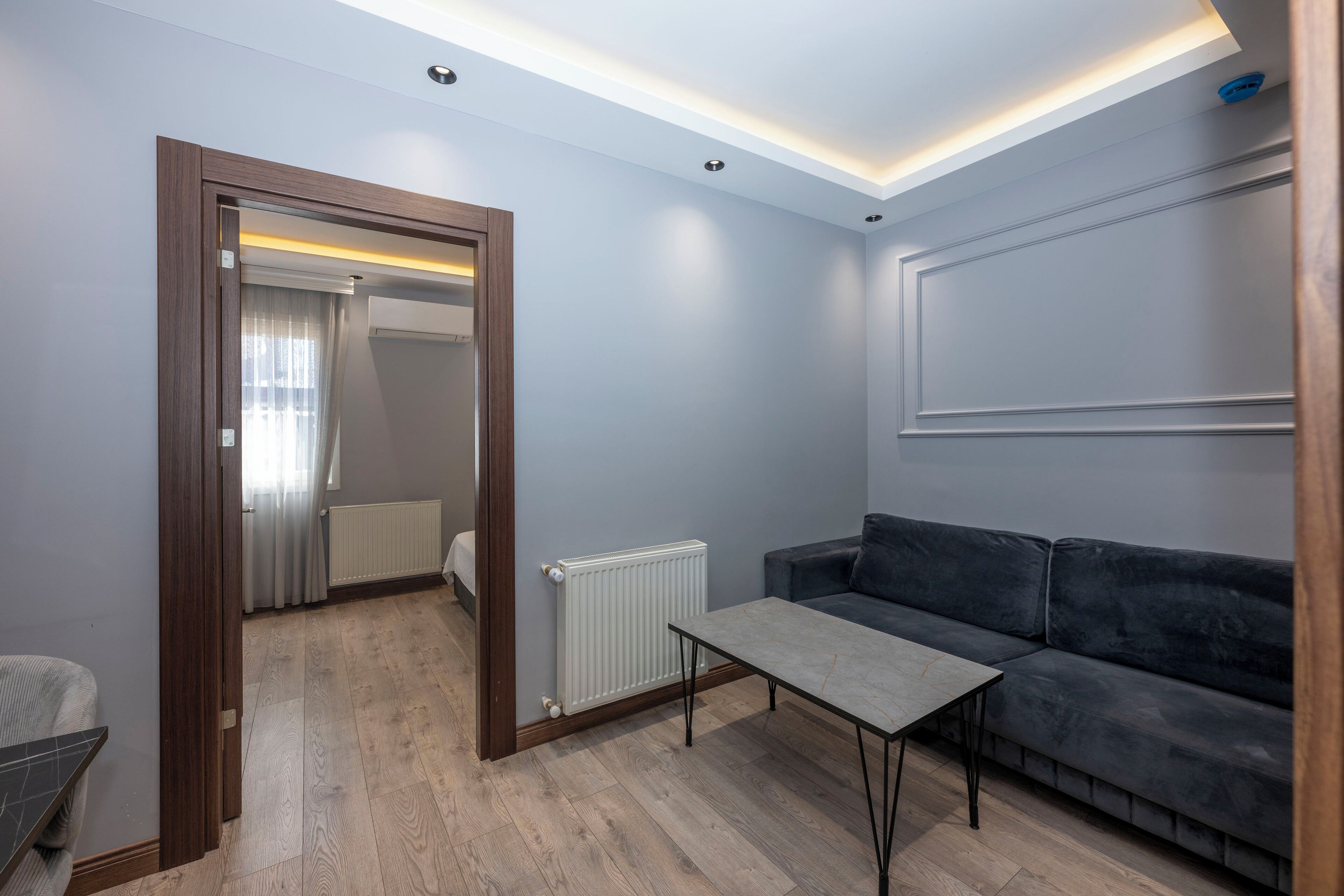 A modern living room with a grey sofa, a small table, and a wooden floor.