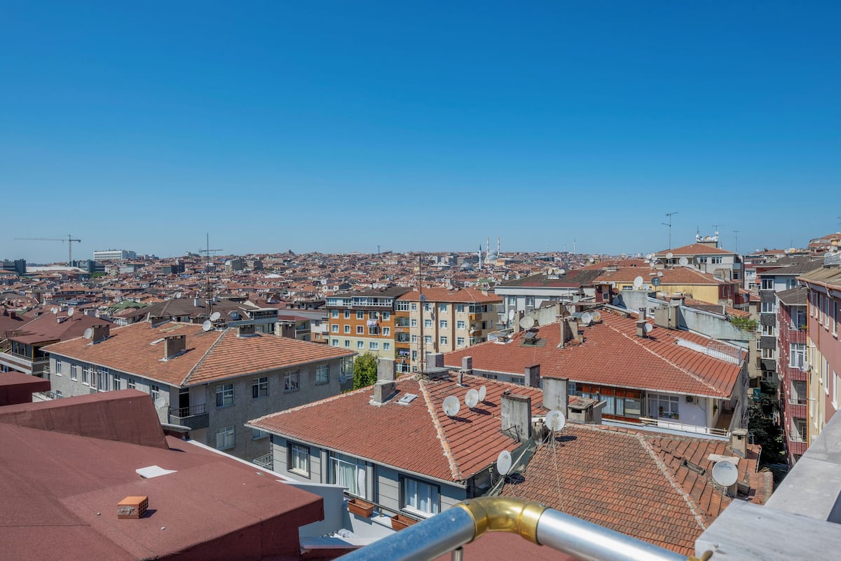 A cityscape with a mix of residential and commercial buildings, featuring red-tiled roofs and various architectural styles.