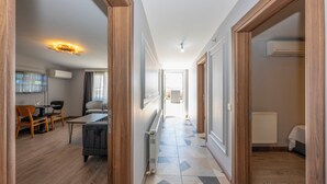Een gang met een eethoek, een radiator en een bed in een slaapkamer.