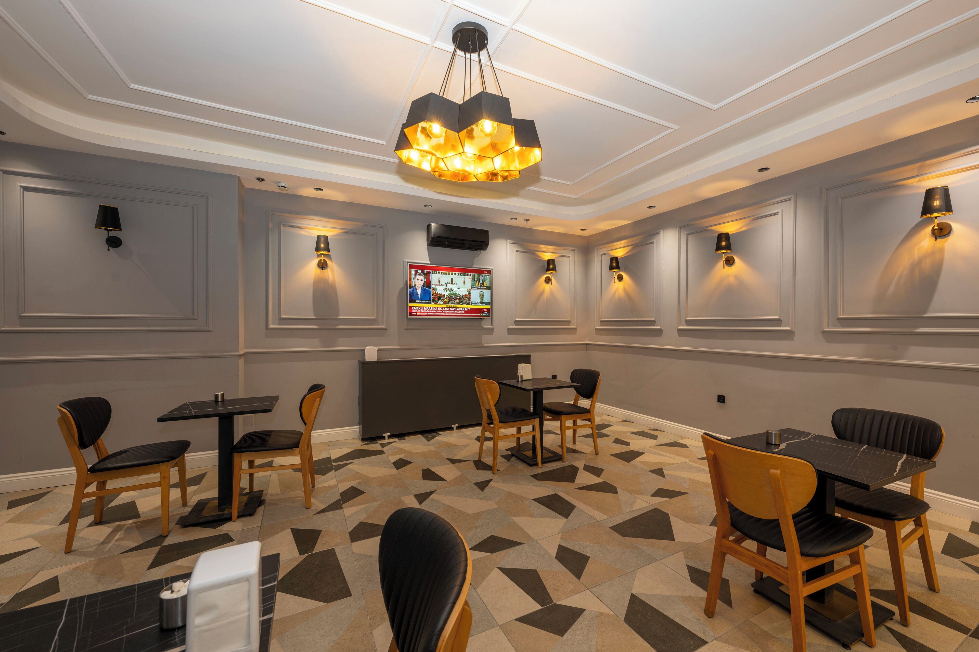 A conference room with a modern chandelier, multiple tables and chairs, and wall-mounted lighting.