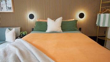 Een moderne slaapkamer met een lattenhouten hoofdbord, een bed met een oranje sprei en twee kussens.