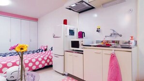 Una camera compatta con un letto, angolo cottura e bagno.