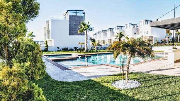 A modern hotel with a swimming pool, palm trees, and a clear sky. - 🌄Papas&Beer✔️ PuertoNuevo✔️ Valle ✔️ Ensenada✔️ (Rosarito)