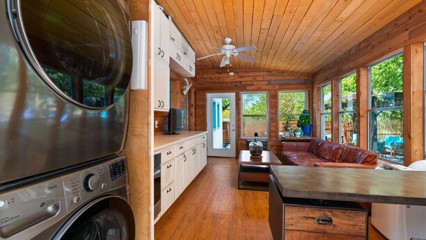 A compact kitchen with wooden cabinets, a built-in washer, and a ceiling fan. - Boho-Ranch Retreat in Hip East Austin w Hot Tub and Cowgirl pool. (Austin)