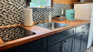A modern kitchen with a wooden countertop, stainless steel sink, and black cabinets.