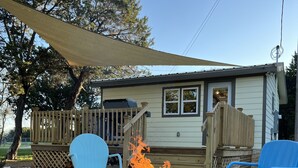 A backyard with a stone fire pit, two chairs, and a wooden deck.