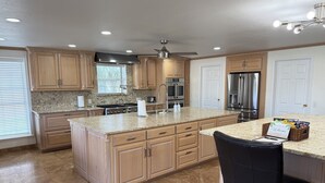Una cocina amplia con encimeras de granito, armarios de madera y electrodomésticos de acero inoxidable.