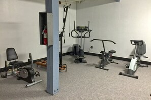 Un gimnasio con diverso equipo de ejercicio, incluyendo una caminadora, bicicleta estática y máquinas de pesas.