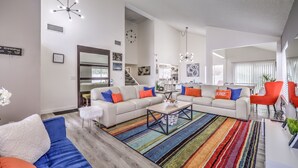 Ein modernes Wohnzimmer mit einer Sofagarnitur, einem Couchtisch und einem farbenfrohen Streifen Teppich.