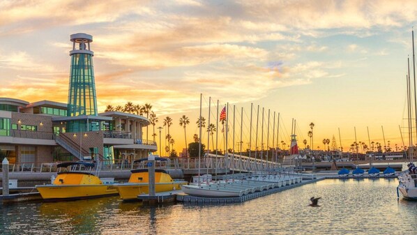 A marina with boats docked, a lighthouse, and a building with a glass facade.