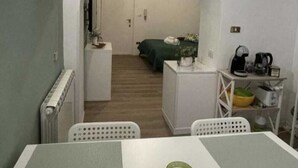 A compact room with a dining table, a small green candle, a kitchenette, a bed, and a radiator. - The ideal home for your stay in Rome  (Roma)
