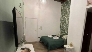 A bedroom with a bed, a bedside table, a mirror, a hanging light fixture, and a door. - The ideal home for your stay in Rome  (Roma)