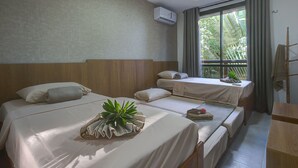 Hotelkamer met twee bedden, een raam met gordijnen, een airconditioning en een kleine tafel met een plant.