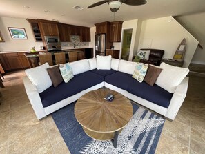 Un salon moderne avec un canapé d’angle, une table basse et une cuisine en arrière-plan.