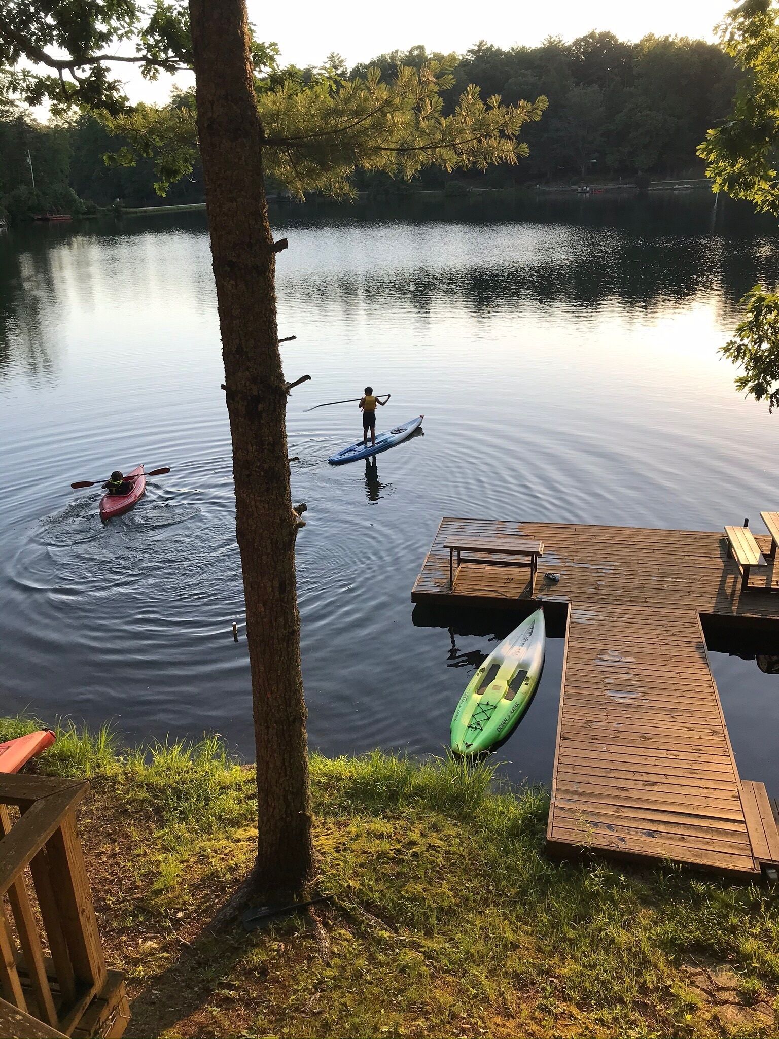A calm lake with kayaks and a dock.