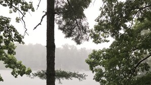 Une jetée en bois s’étendant dans un lac brumeux, entourée d’arbres.